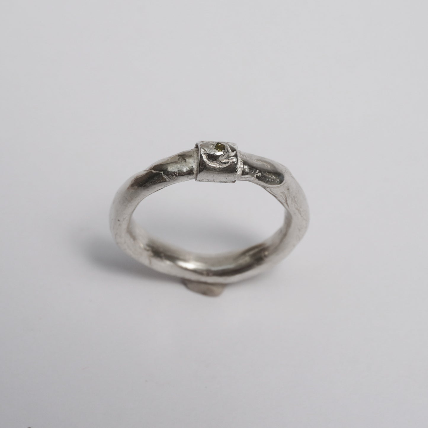 Artisanal handmade silver ring with sculptural organic band, featuring a central green zirconia stone. Unique one-of-a-kind design crafted in solid 925 sterling silver using the traditional lost-wax technique. Elegant, raw, slightly irregular surface with a minimal yet expressive form, created by a contemporary jewelry artist in Porto.