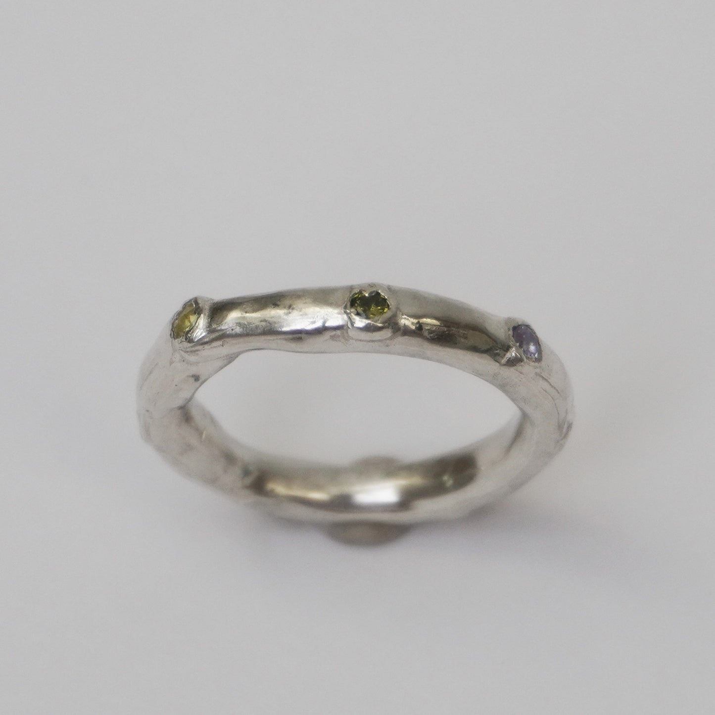 Artisanal handmade silver ring with organically shaped polished band, featuring multiple colorful synthetic zirconia stones set into the surface. Unique one-of-a-kind jewelry piece crafted in solid 925 sterling silver using the lost-wax casting method. Minimalist yet playful design, ethically made in a small Porto-based studio.