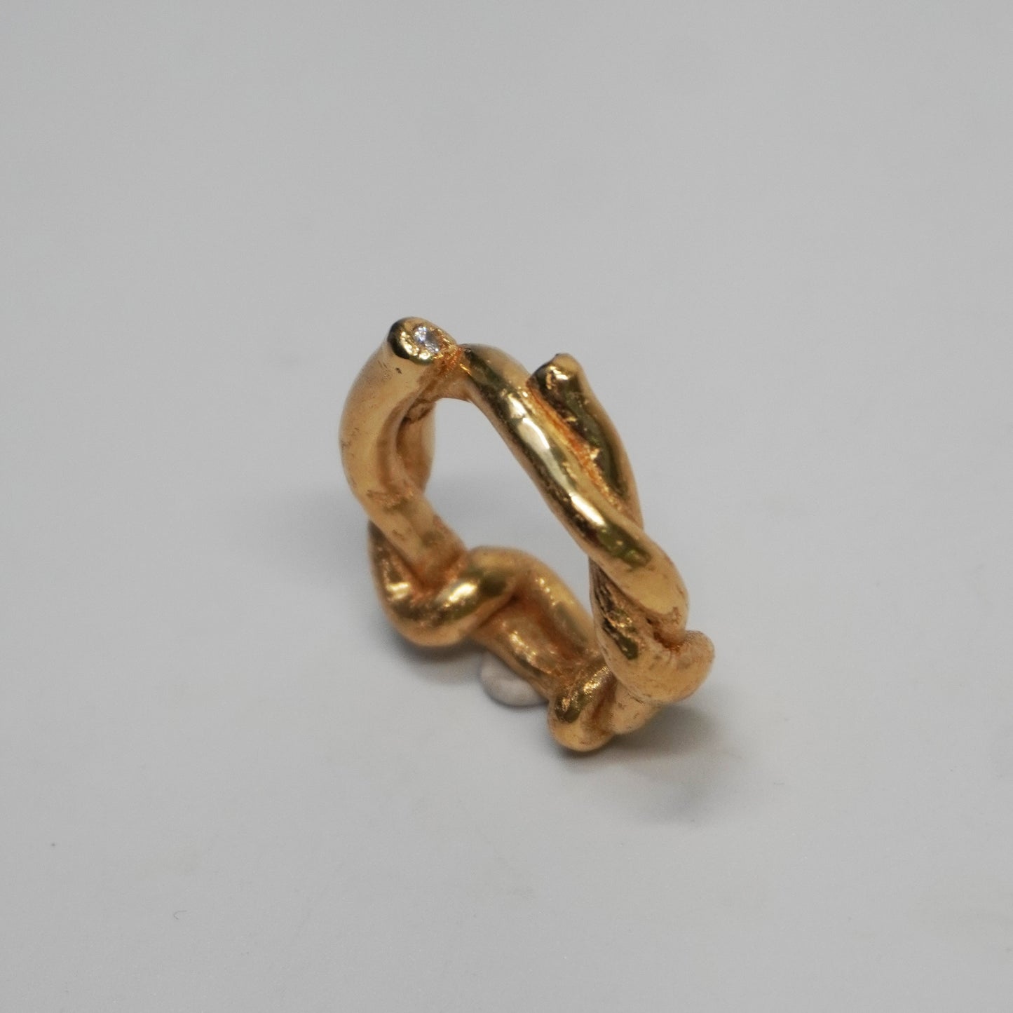 Handmade chunky ring made from 24k gold-plated brass with a sculptural twisted form and a small clear zirconia stone. Artisan piece crafted using the lost-wax casting technique in a Porto-based studio. One-of-a-kind bold statement ring with polished finish.