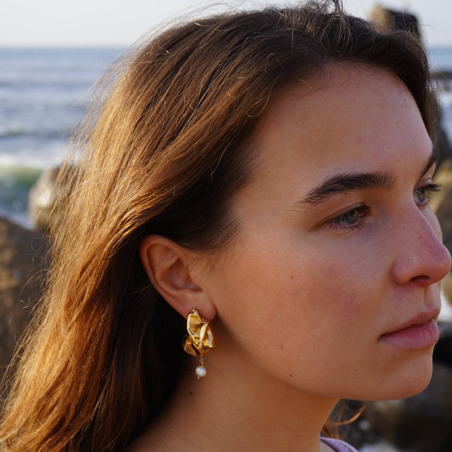 Artisanal handmade gold sculptural earrings with organic asymmetrical form and freshwater pearl, inspired by nature