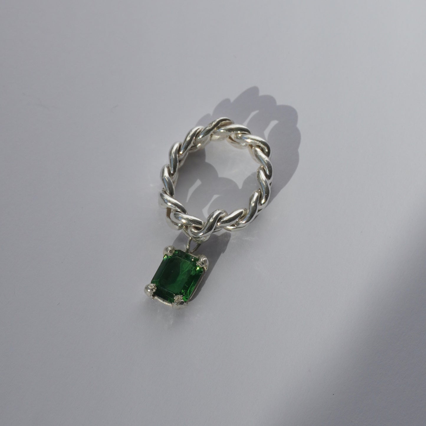 Handcrafted silver ring with twisted band and hanging emerald-cut green gemstone