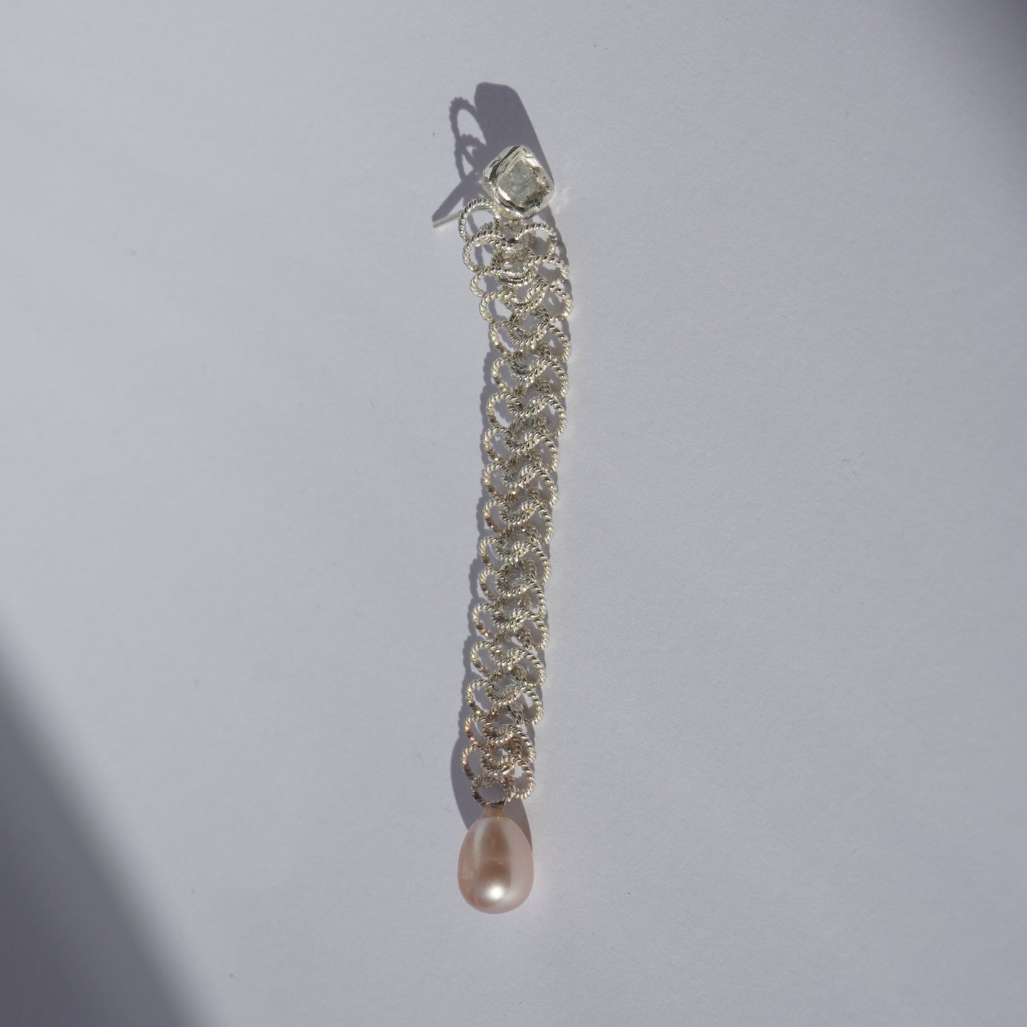 Handcrafted silver earring with lace-like chain, freshwater pearl, and hand-set gemstone
