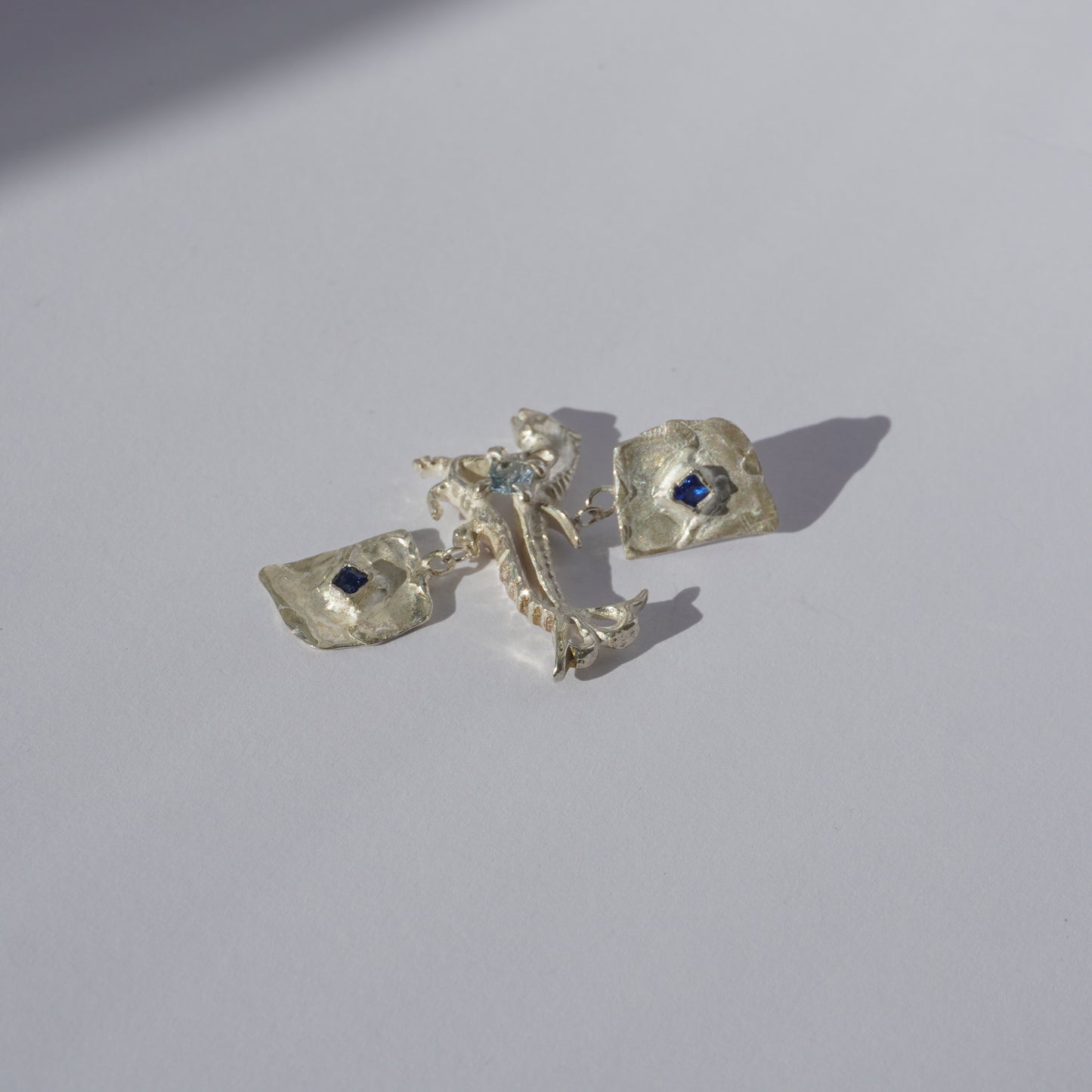 Handcrafted sterling silver earrings with organic sculptural forms and blue hand-set gemstones