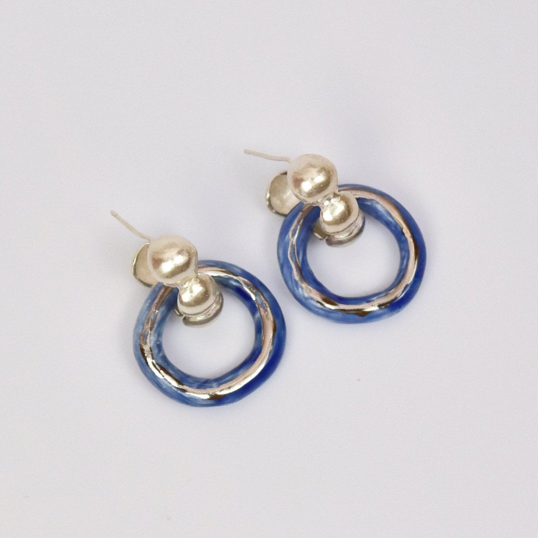 Artisanal handmade porcelain hoop earrings with glossy blue and gold or silver enamel finish. Unique ceramic design with gold stud posts, perfect for modern, minimalist, and statement jewelry lovers. Lightweight artisanal hoops for everyday wear or special occasions.
