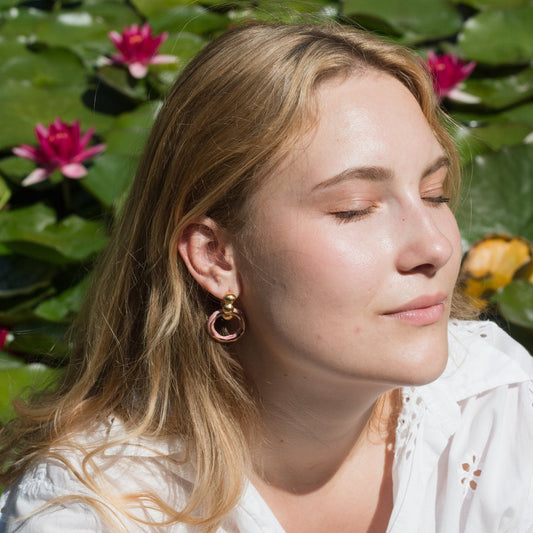 Handmade porcelain hoop earrings featuring a unique circular design with a glossy pink/ and gold enamel finish. These artisanal ceramic earrings are mounted on gold-toned studs with a minimalist yet bold aesthetic. The combination of smooth porcelain and shimmering enamel creates an eye-catching, modern statement piece, perfect for artistic, boho, or contemporary fashion styles. Ideal for everyday wear or special occasions, these earrings reflect a handcrafted, elegant charm.