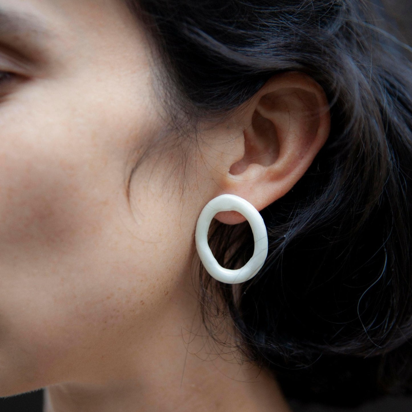 Handmade White Porcelain Hoop Earring With Organic Open Circle Design, Worn as a Bold Stud. Lightweight Ceramic Statement Earring for Minimalist and Contemporary Jewelry Styles.