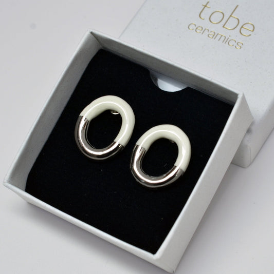 Artisanal Handmade Porcelain Earrings With a Modern Two-Tone Design – Half Natural White Ceramic, Half Glazed in Either Gold or Silver. Lightweight Oval-Shaped Hoops That Blend Minimalist Elegance With a Bold, Contemporary Look. Perfect for Statement Jewelry Lovers Seeking Unique, Handcrafted Pieces.