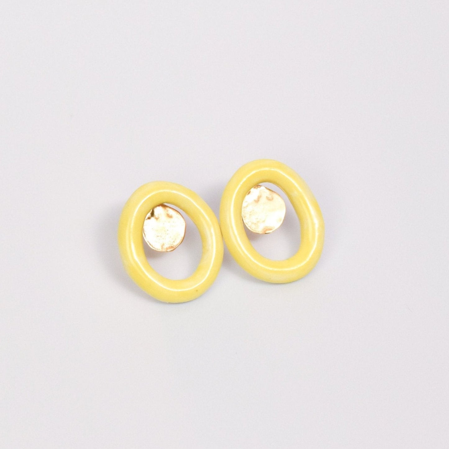 Artisanal handmade yellow porcelain stud earrings with unique oval hoop design and hammered gold detail. Lightweight and modern ceramic earrings, perfect for minimalist or statement jewelry styles. Ideal for everyday wear or as a thoughtful handmade gift