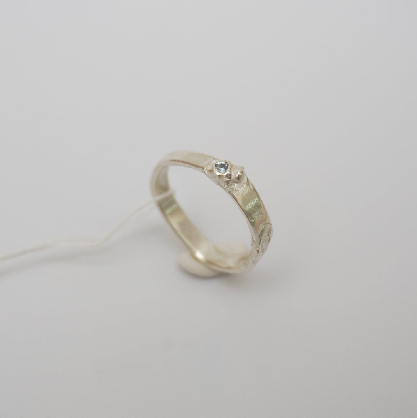 handcrafted sterling silver ring featuring a wave-like design and textured details, light blue zirconia stone