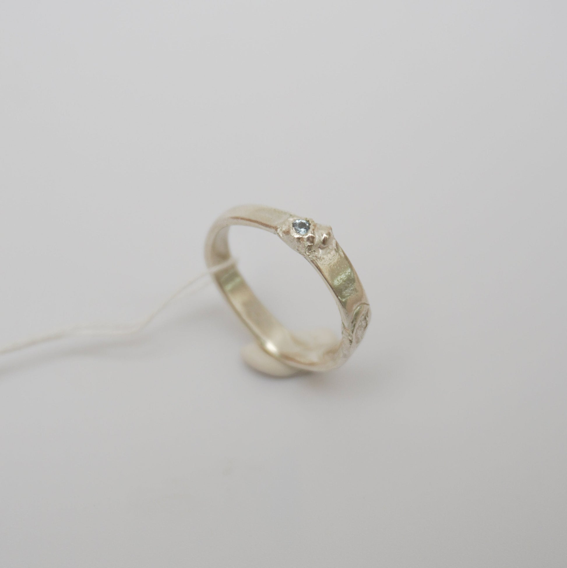 handcrafted sterling silver ring featuring a wave-like design and textured details, light blue zirconia stone