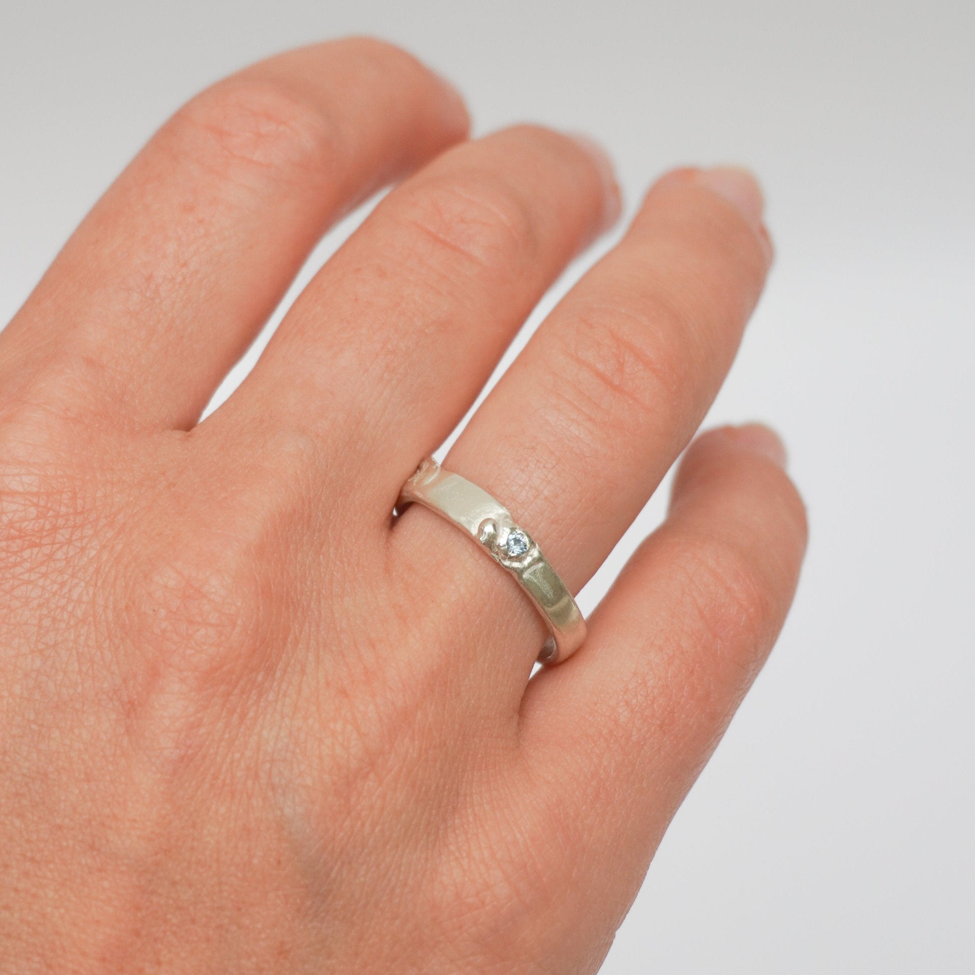 handcrafted sterling silver ring featuring a wave-like design and textured details, light blue zirconia stone