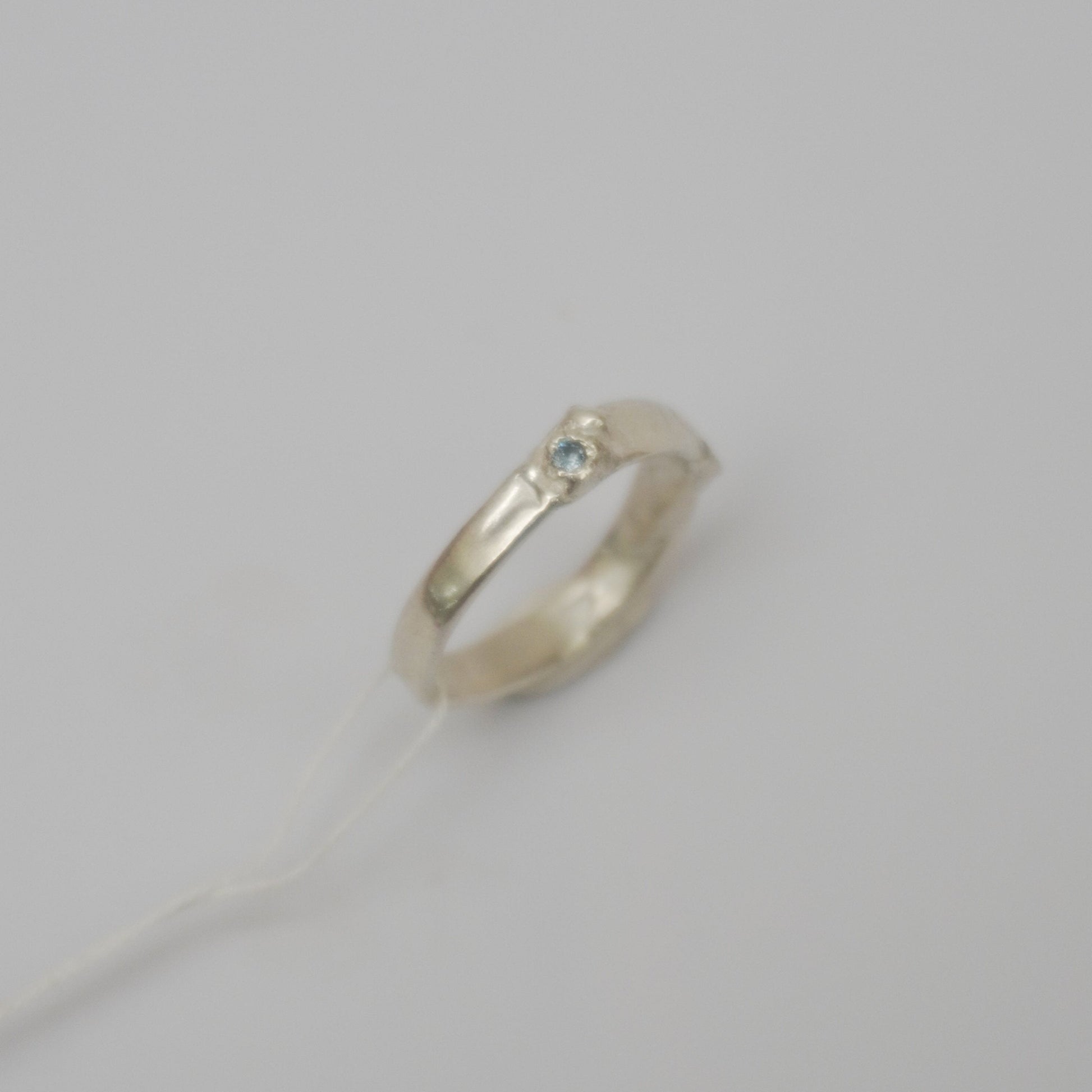 handcrafted sterling silver ring featuring a wave-like design and textured details, light blue zirconia stone