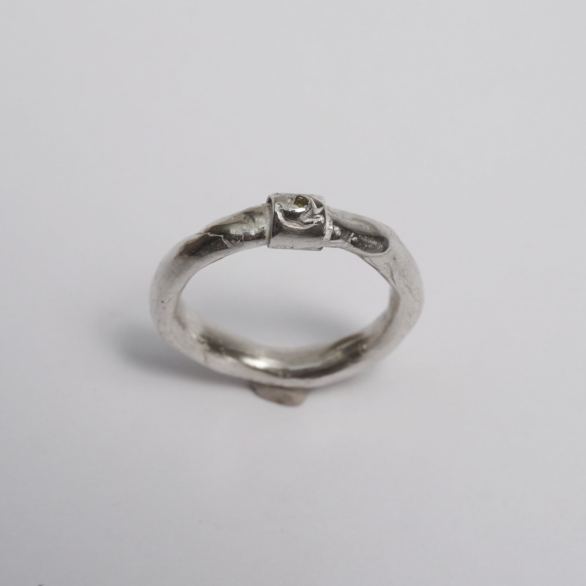 Artisanal handmade silver ring with sculptural organic band, featuring a central green zirconia stone. Unique one-of-a-kind design crafted in solid 925 sterling silver using the traditional lost-wax technique. Elegant, raw, slightly irregular surface with a minimal yet expressive form, created by a contemporary jewelry artist in Porto.