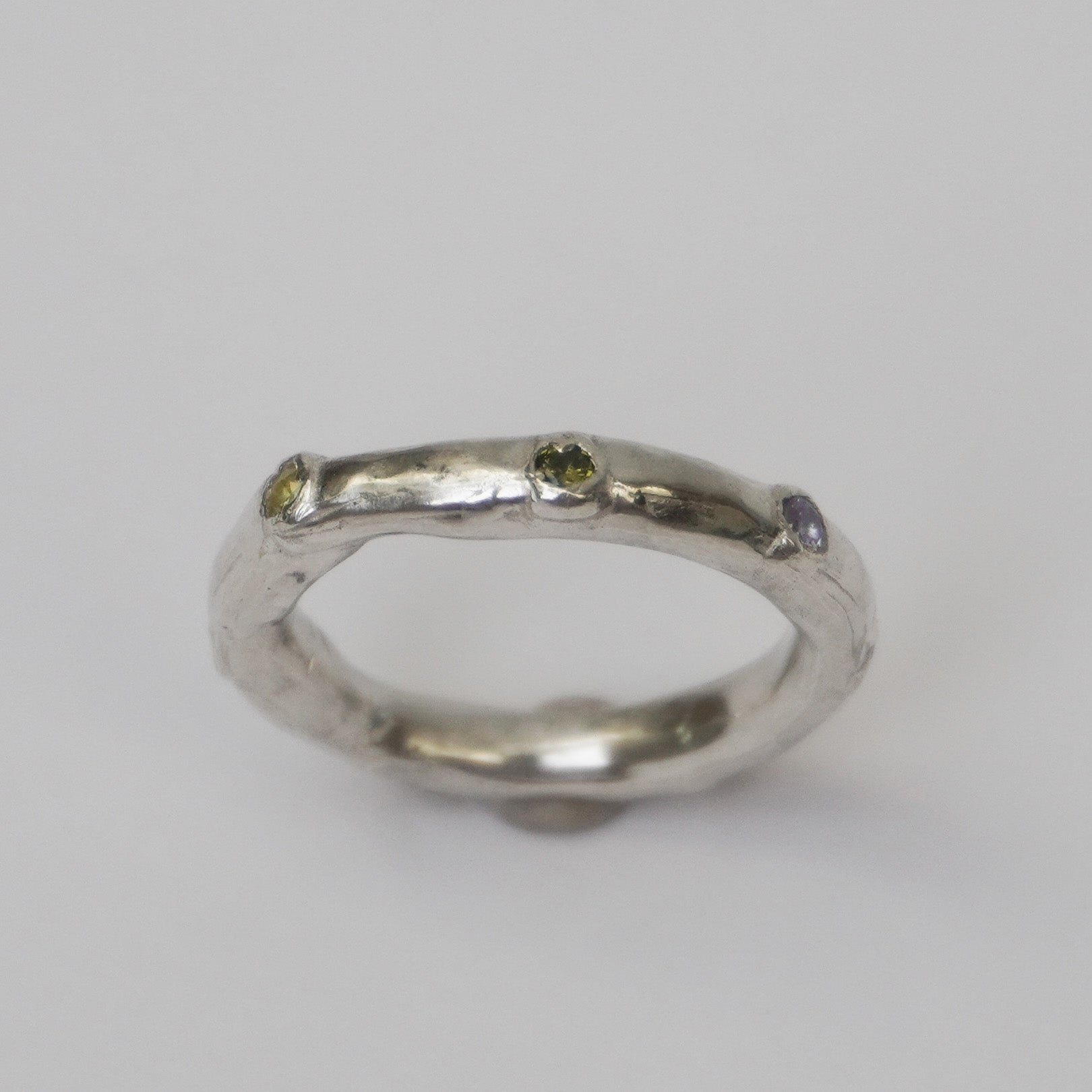 Artisanal handmade silver ring with organically shaped polished band, featuring multiple colorful synthetic zirconia stones set into the surface. Unique one-of-a-kind jewelry piece crafted in solid 925 sterling silver using the lost-wax casting method. Minimalist yet playful design, ethically made in a small Porto-based studio.