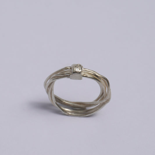 Handmade artisanal silver ring featuring multiple interwoven bands fused into a single unique form, accented by a small raised detail with an embedded clear zirconia stone. Crafted using the lost-wax casting technique in a Porto-based studio, this one-of-a-kind piece embodies slow design and sculptural elegance.