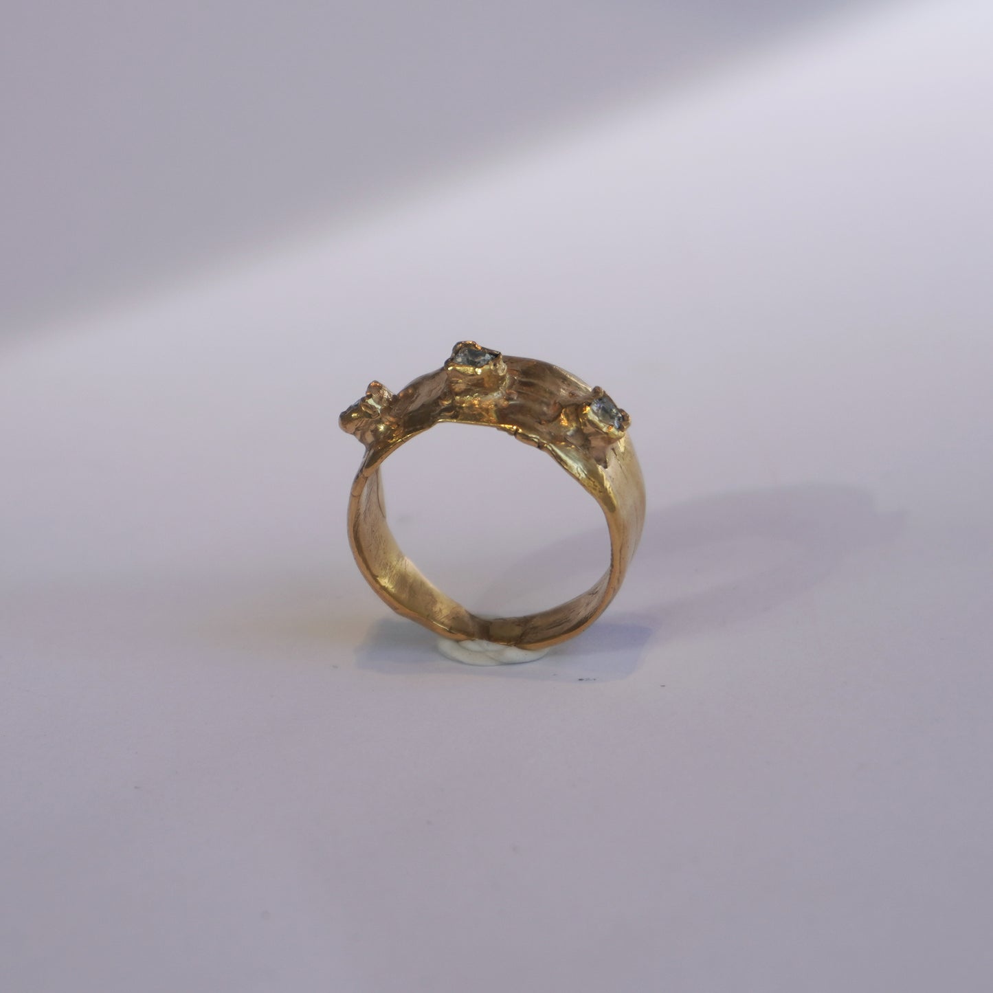 Handcrafted gold ring with organic sculpted band and three set gemstones