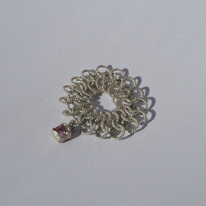 Handcrafted silver ring made of twisted interlinked loops with a hanging pink square-cut gemstone