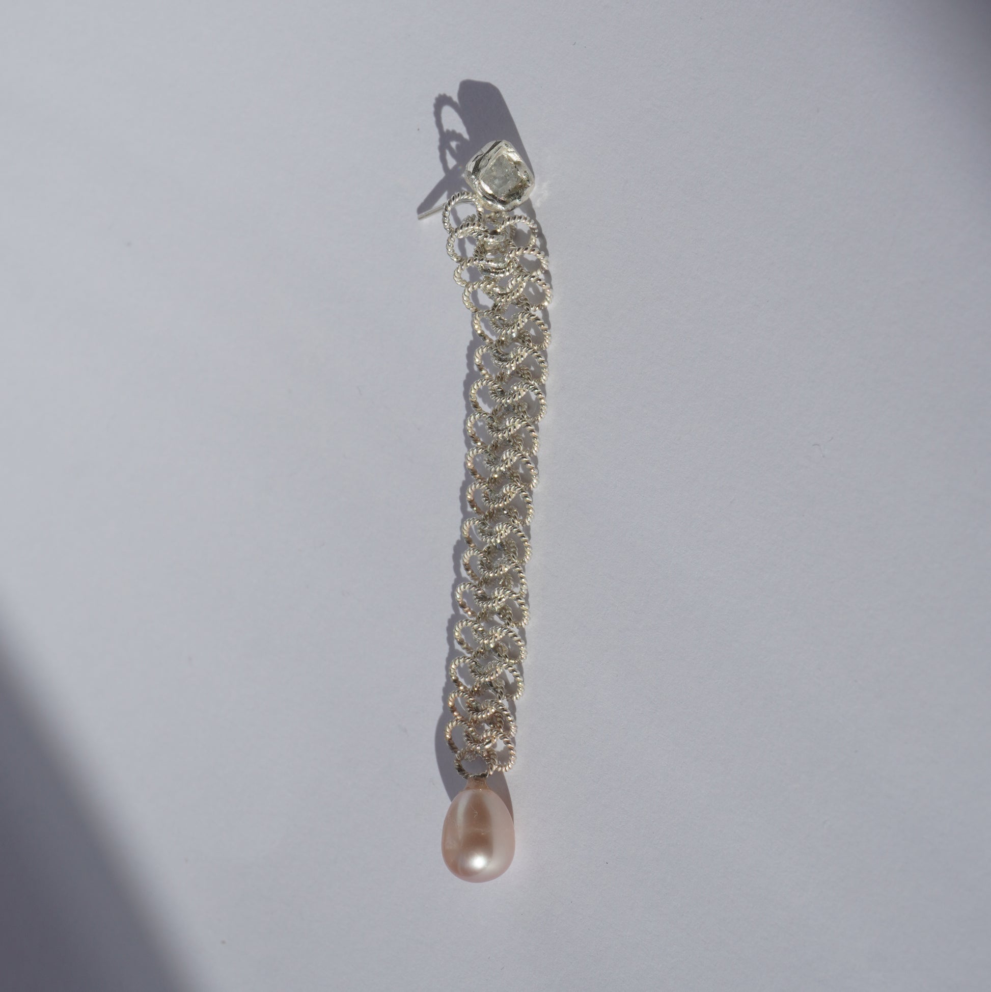 Handcrafted silver earring with lace-like chain, freshwater pearl, and hand-set gemstone