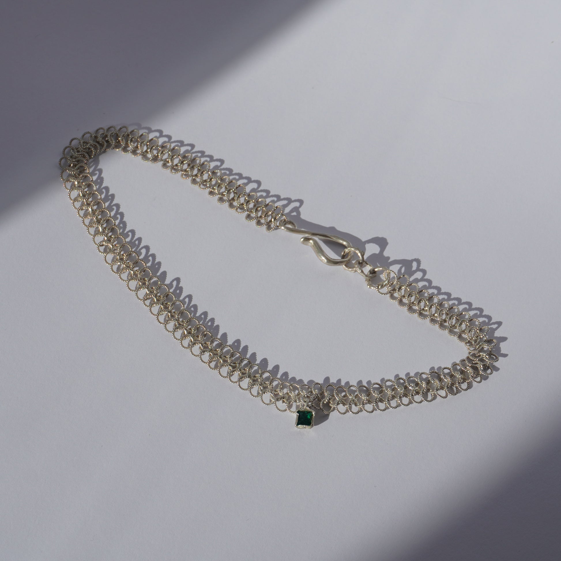 Gold-plated handcrafted double-chain choker with lace-like texture and a small green hand-set gemstone