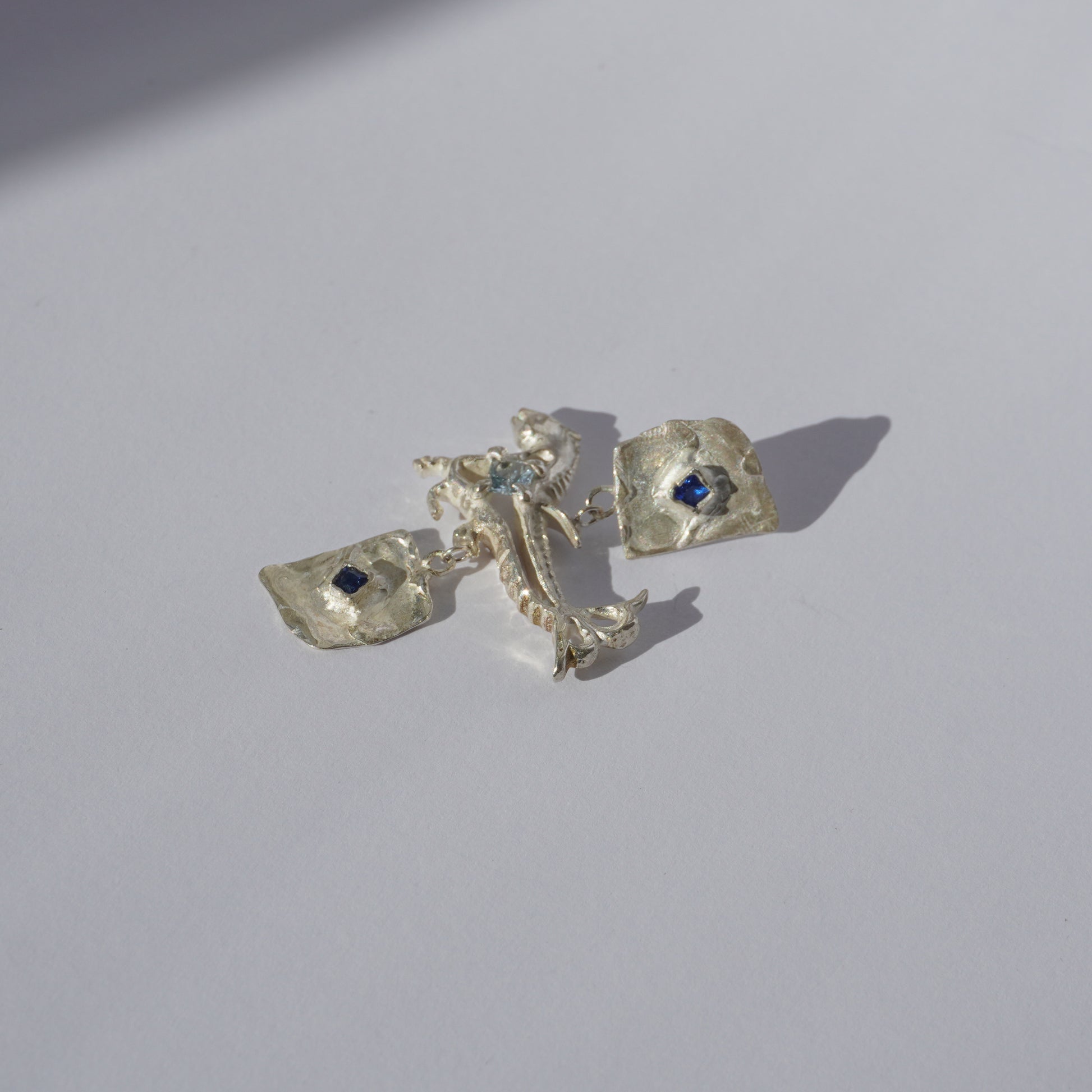 Handcrafted sterling silver earrings with organic sculptural forms and blue hand-set gemstones