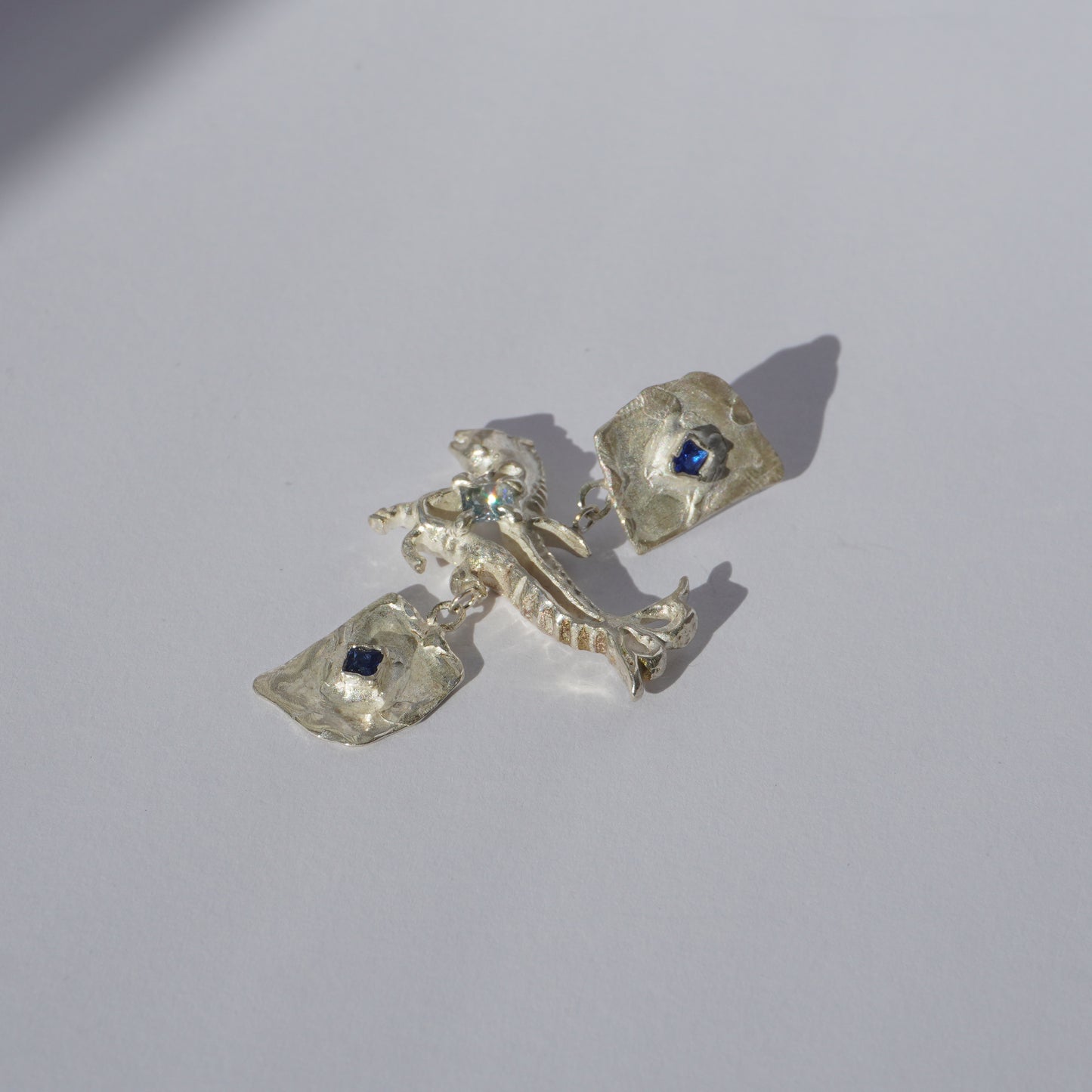 Handcrafted sterling silver earrings with organic sculptural forms and blue hand-set gemstones