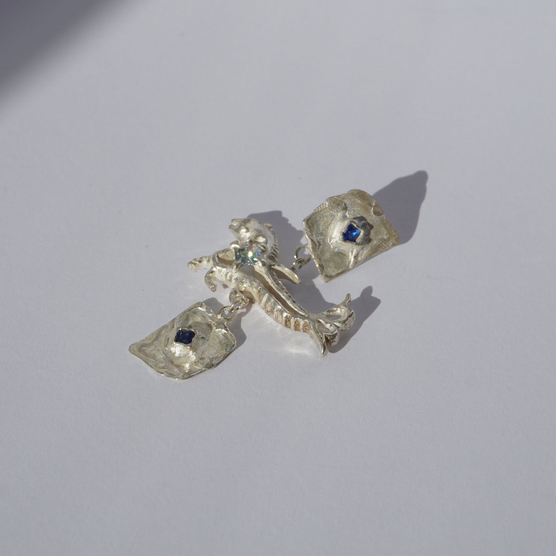 Handcrafted sterling silver earrings with organic sculptural forms and blue hand-set gemstones