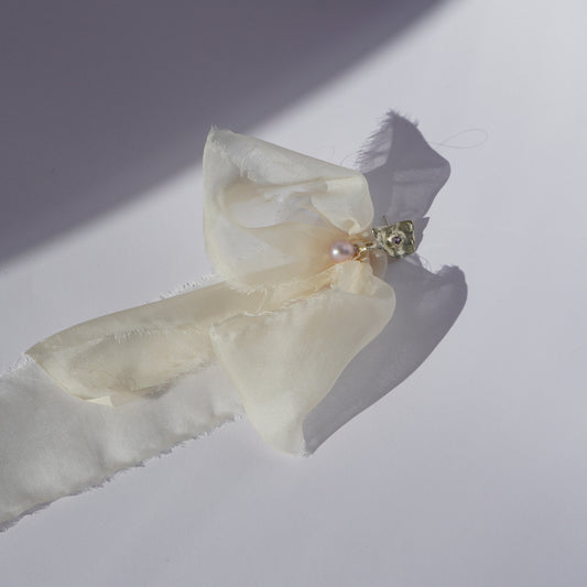 Handcrafted silver earring with sculptural element, hand-set gemstone, freshwater pearl, and soft silk ribbon