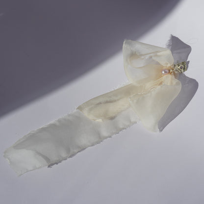 Handcrafted silver earring with sculptural element, hand-set gemstone, freshwater pearl, and soft silk ribbon