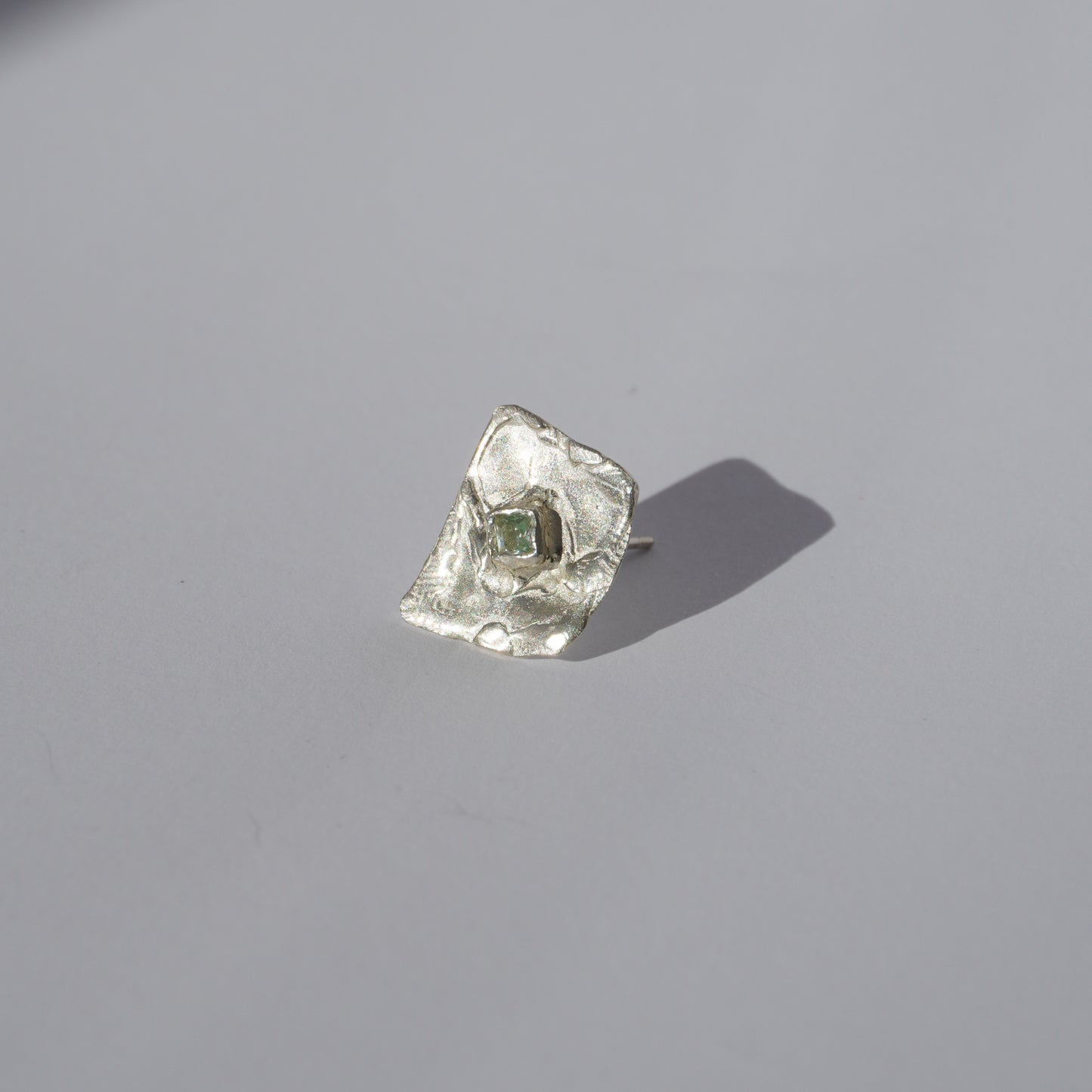 Silver handcrafted stud earrings with organic sculptural surfaces and green hand-set gemstones