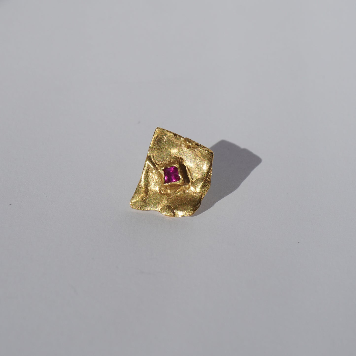 Gold-plated handcrafted stud earrings with organic sculptural surfaces and red hand-set gemstones
