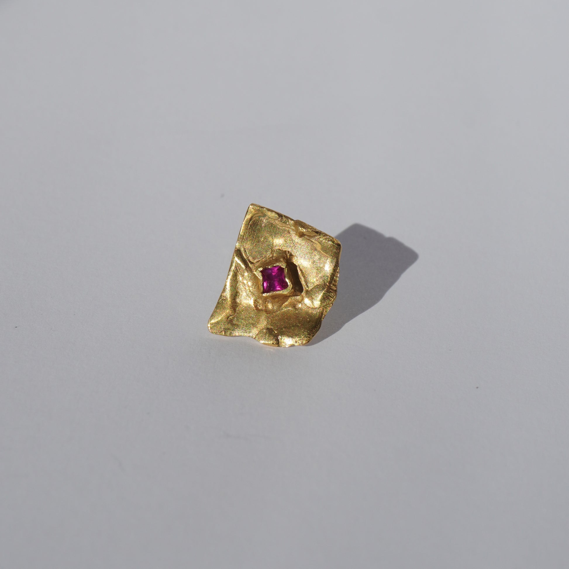 Gold-plated handcrafted stud earrings with organic sculptural surfaces and red hand-set gemstones
