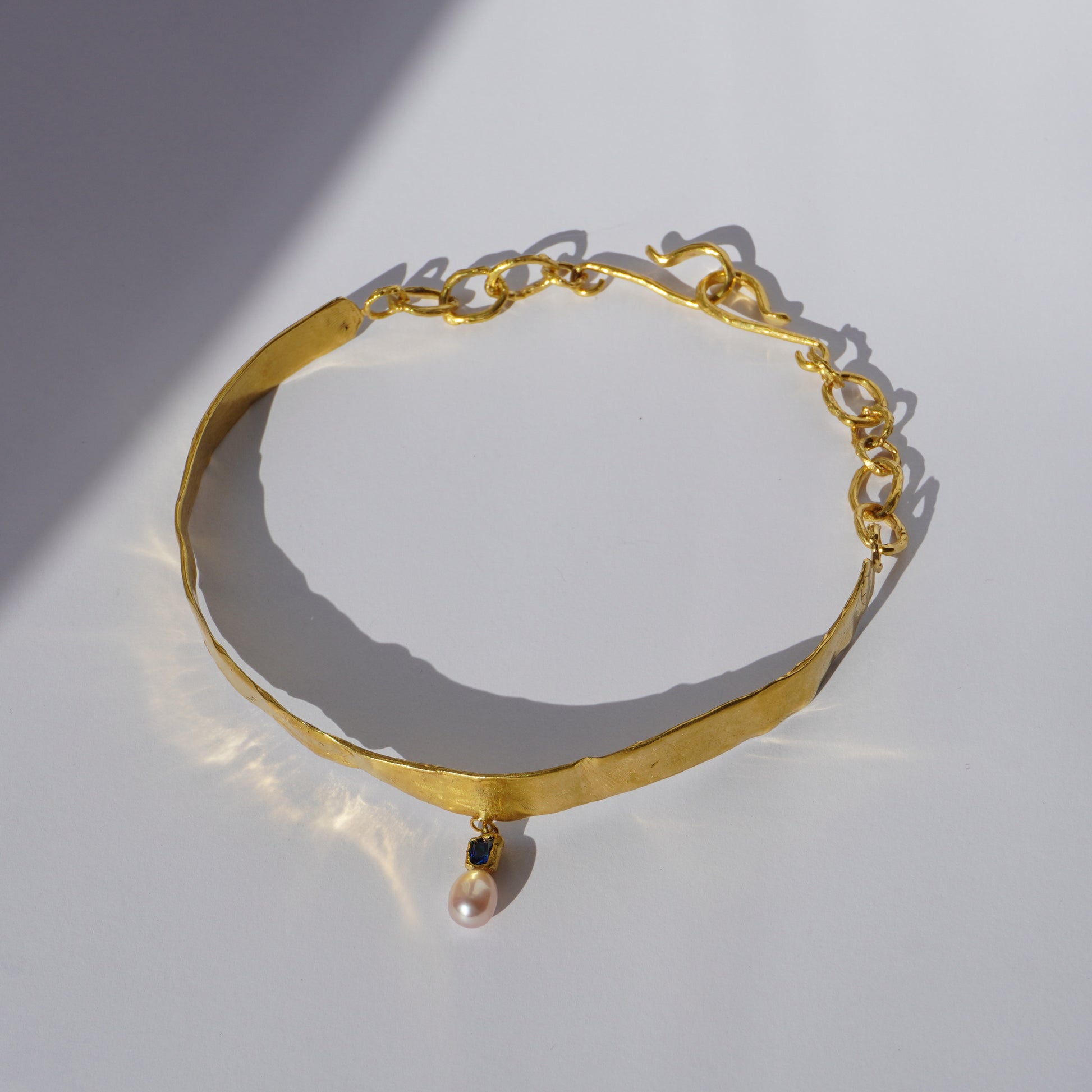 Gold-plated handcrafted choker with sculptural band, hand-set gemstone, and freshwater pearl pendant