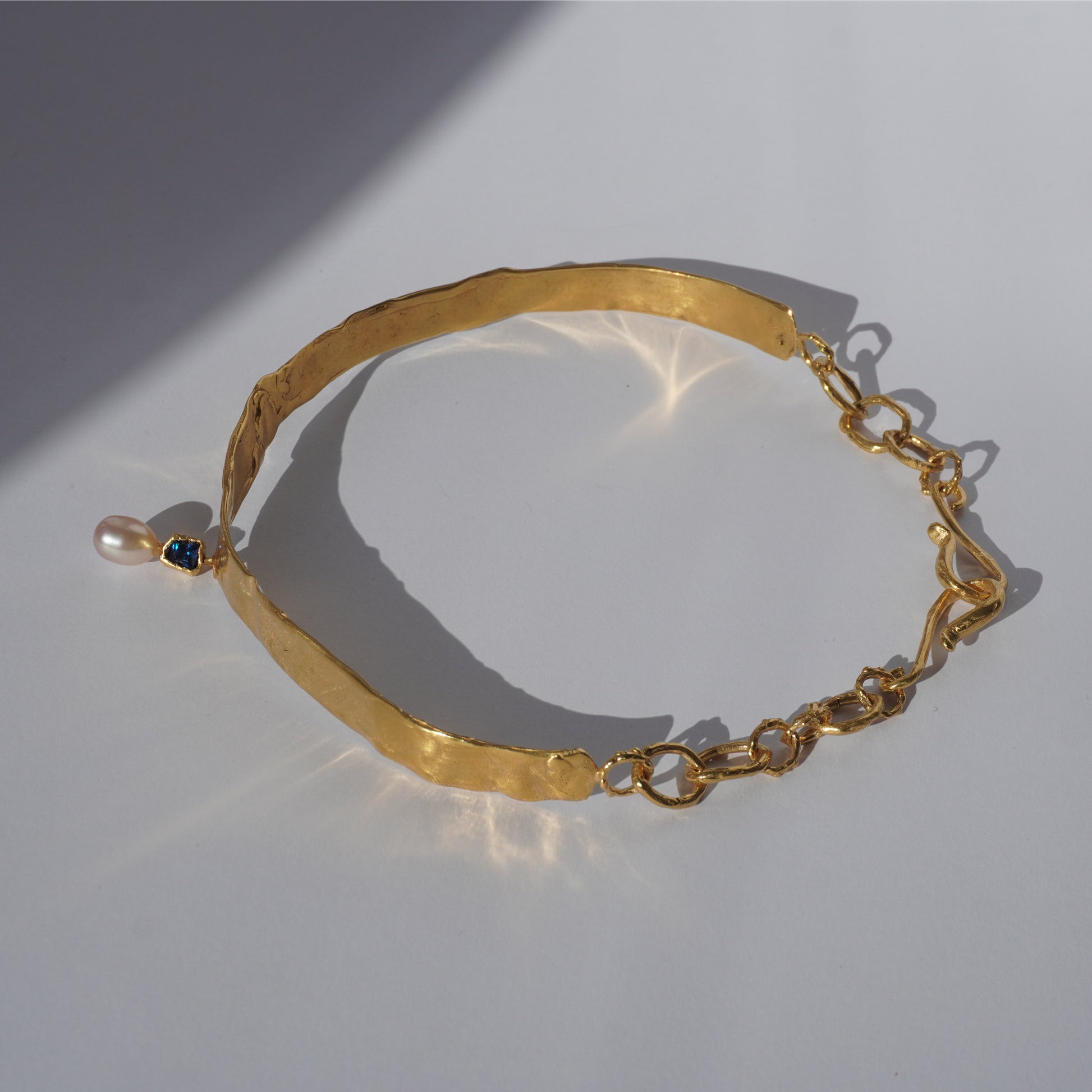 Gold-plated handcrafted choker with sculptural band, hand-set gemstone, and freshwater pearl pendant