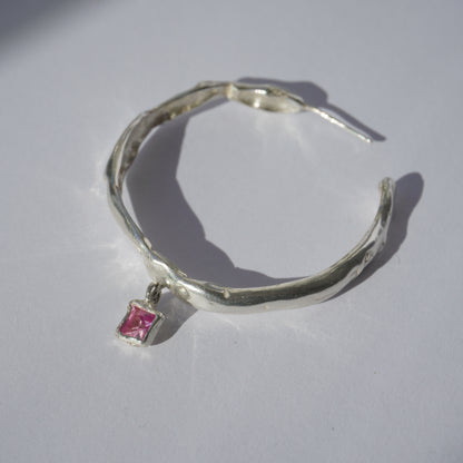 Handcrafted silver hoop earring with irregular organic shape and pink hand-set gemstone