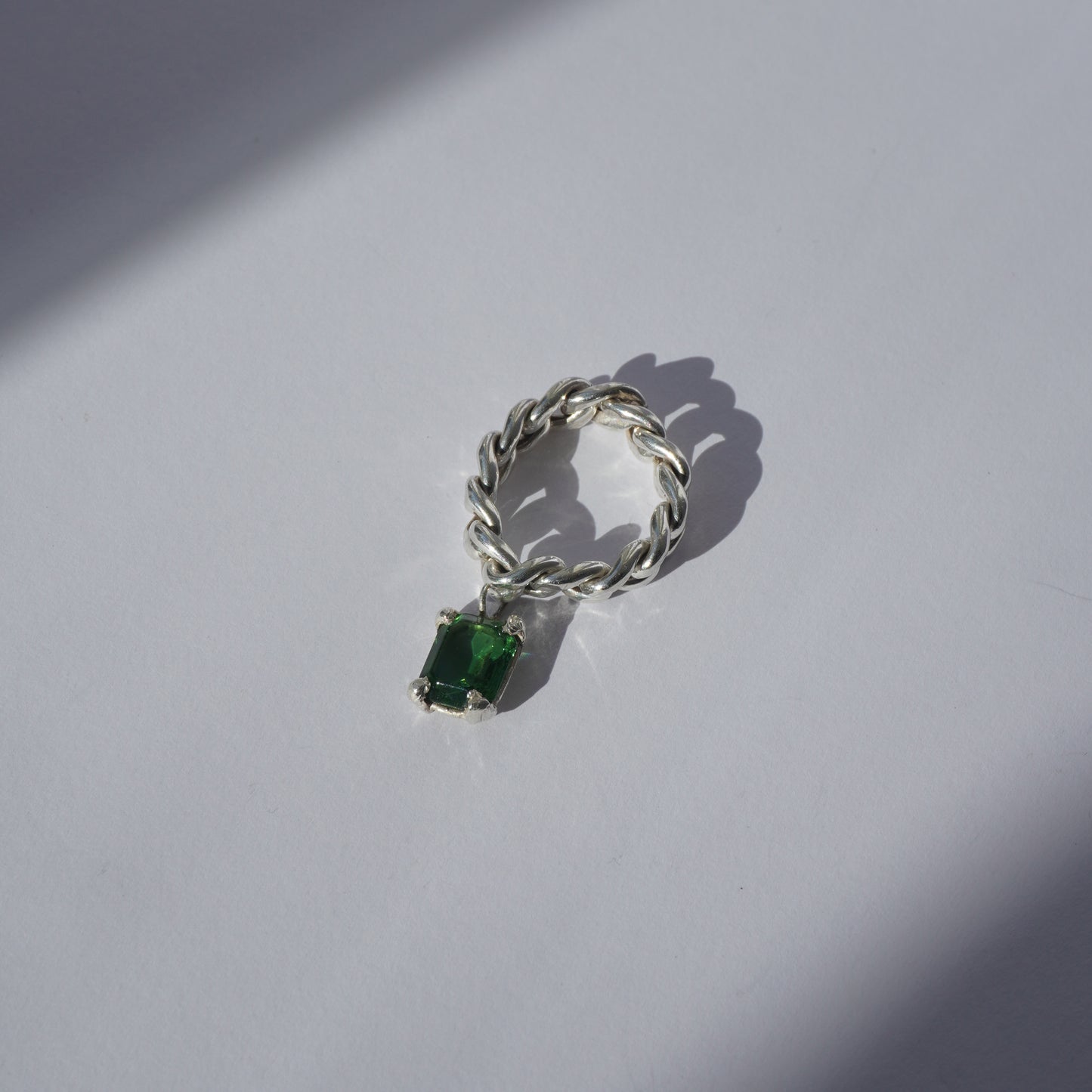 Handcrafted silver ring with twisted band and hanging emerald-cut green gemstone