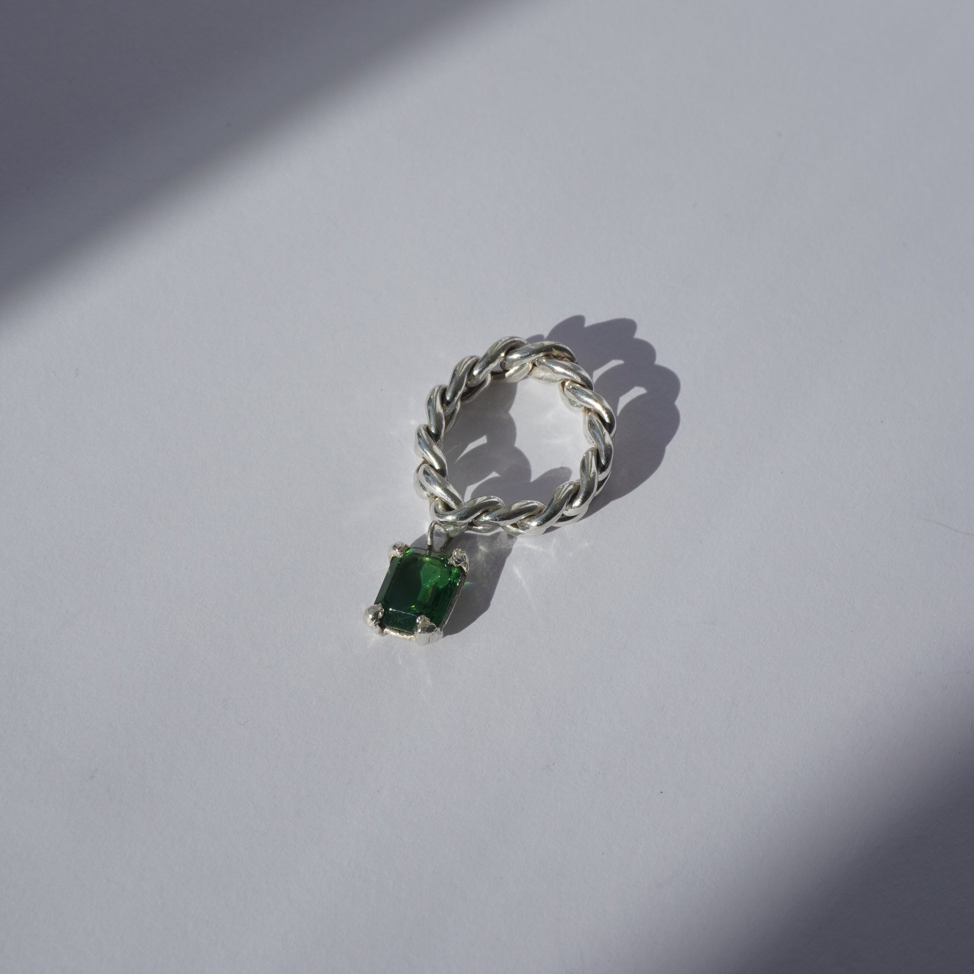 Handcrafted silver ring with twisted band and hanging emerald-cut green gemstone
