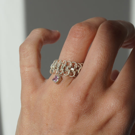 Handcrafted silver ring made of twisted interlinked loops with a hanging pink square-cut gemstone