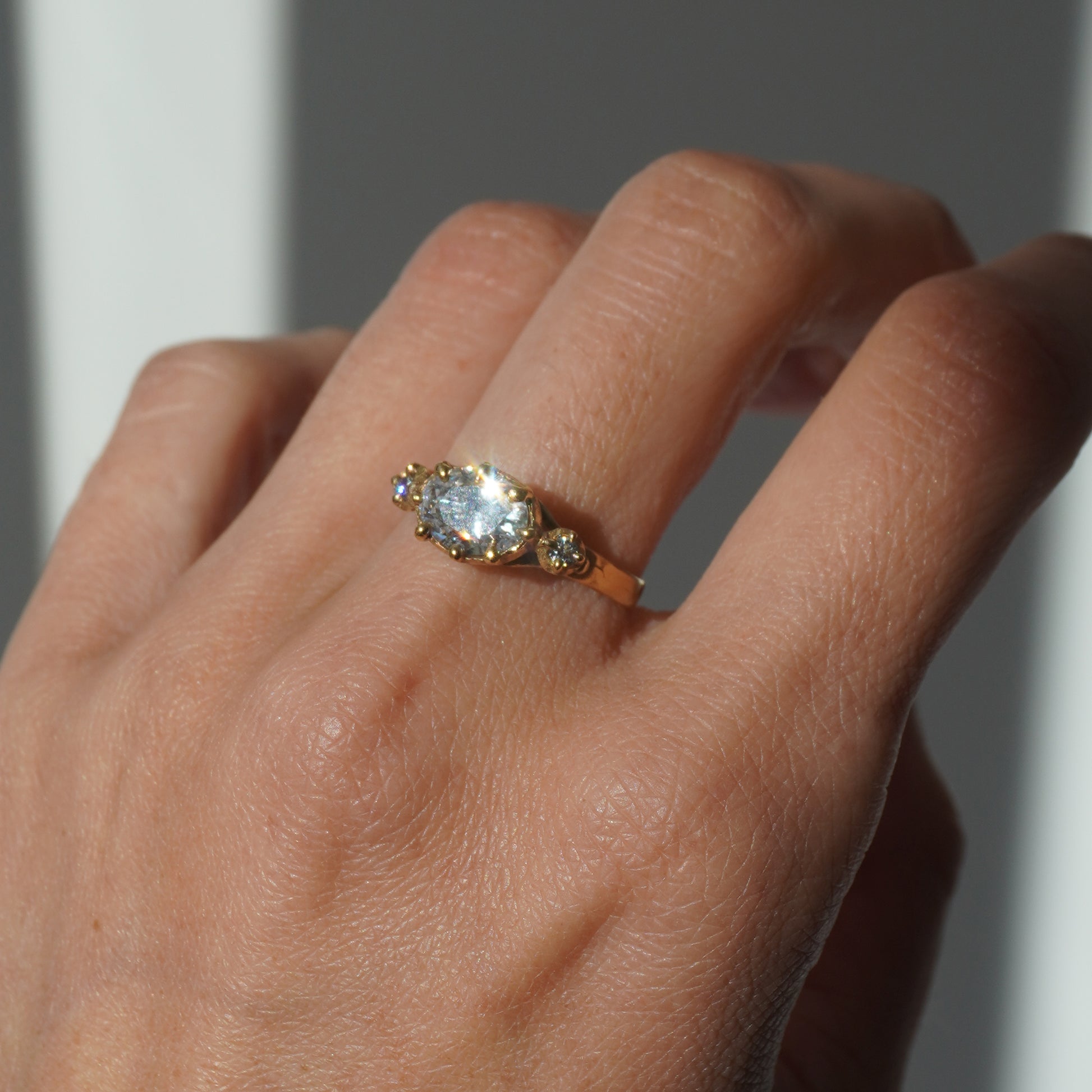 Handcrafted golden ring with oval gemstone and two side stones, worn on a hand