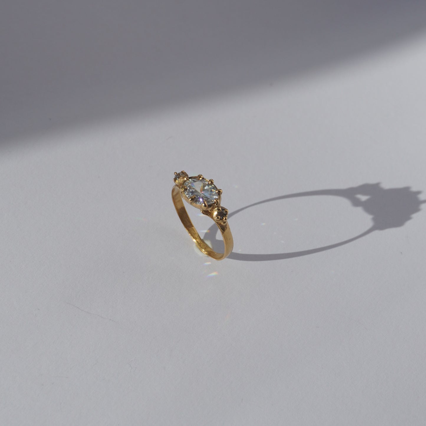 Handcrafted golden ring with oval gemstone and two side stones, worn on a hand