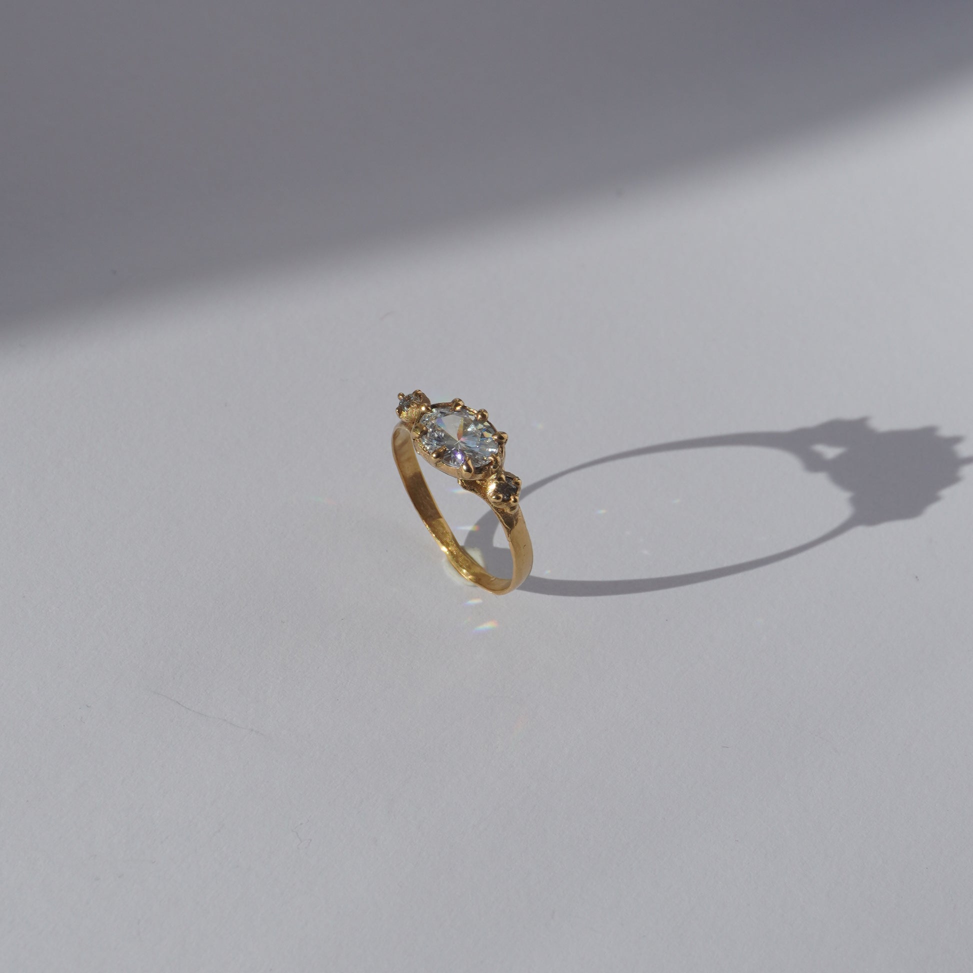 Handcrafted golden ring with oval gemstone and two side stones, worn on a hand