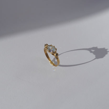 Handcrafted golden ring with oval gemstone and two side stones, worn on a hand