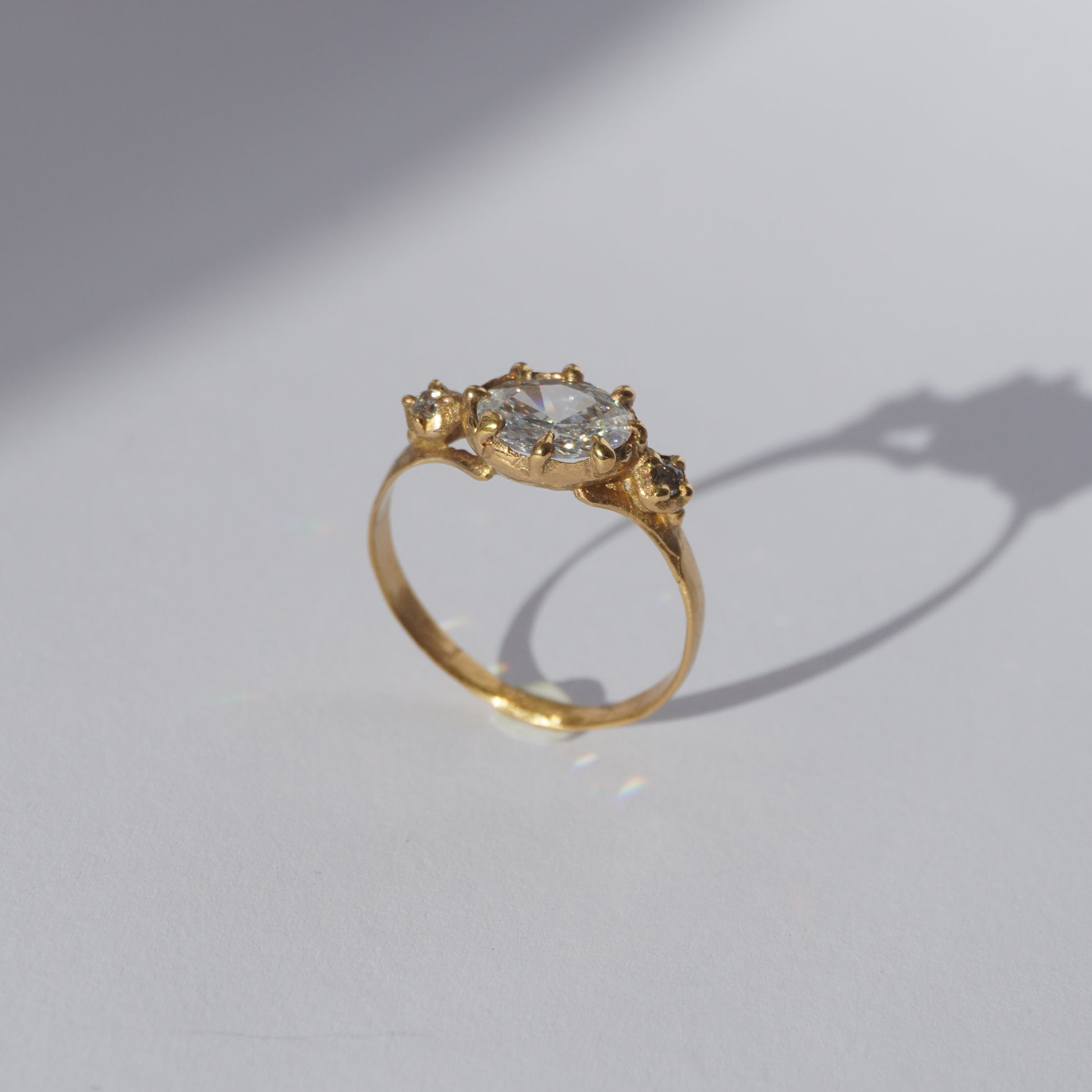 Handcrafted golden ring with oval gemstone and two side stones, worn on a hand