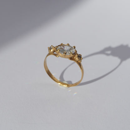 Handcrafted golden ring with oval gemstone and two side stones, worn on a hand