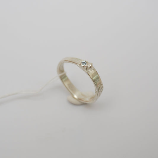 handcrafted sterling silver ring featuring a wave-like design and textured details, light blue zirconia stone